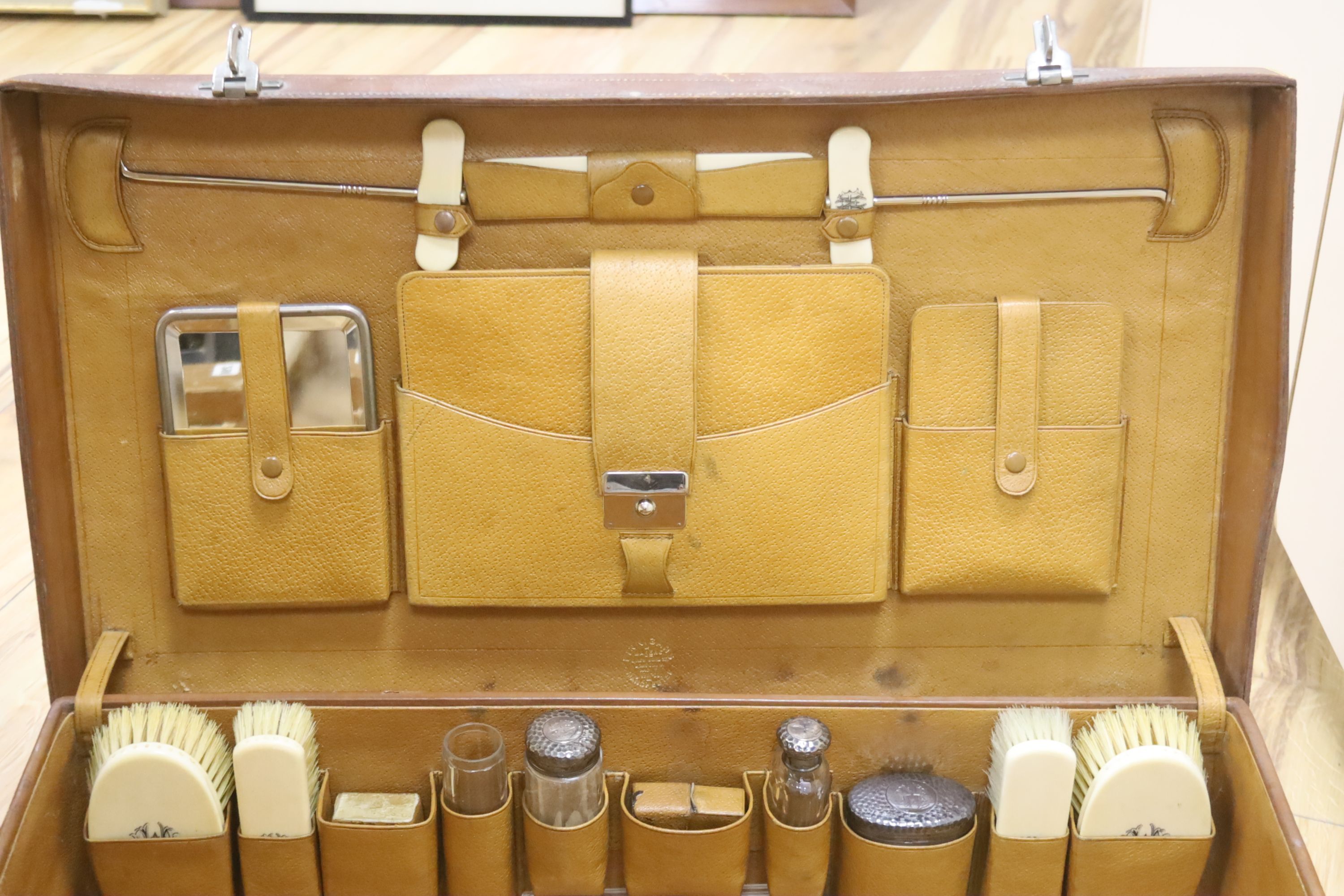 Finnigans of Manchester. A leather case fitted with silver mounted and ivory dressing accessories